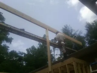 Carpenter setting a ridge beam over a new addition frame — Ice Dam Removal by Roofing Brothers in Conklin