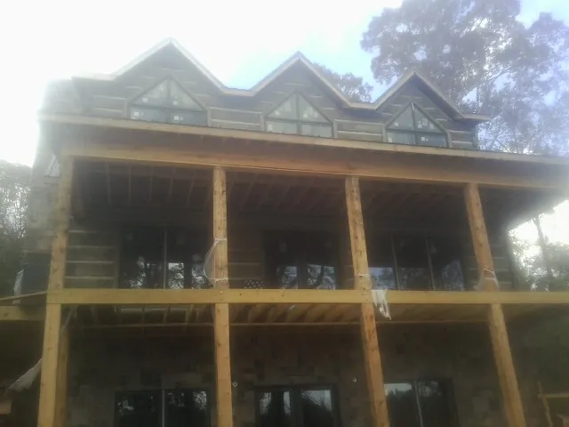 Dormers and porch framing on a large log home under construction — Roof Coating work by our crew in Conklin