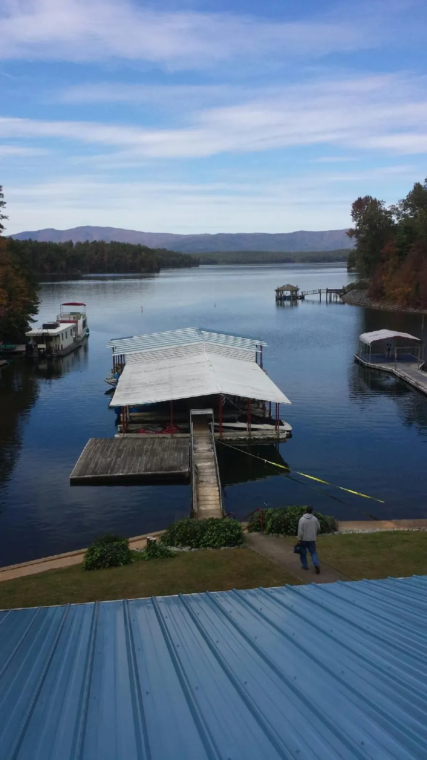View across a lake from a newly installed blue metal roof in Conklin